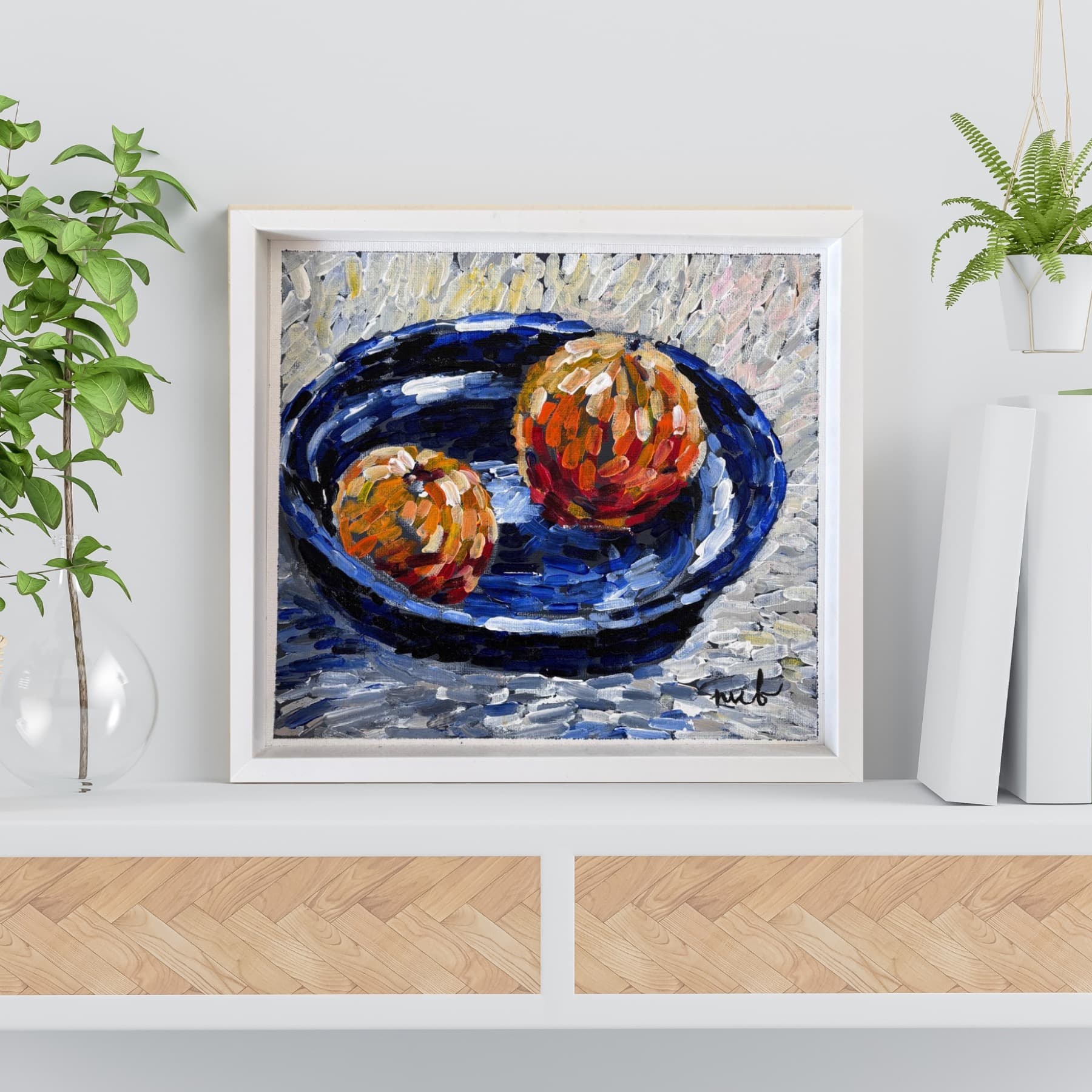 Still Life with Oranges in a white frame, shown on a shelf in an interior setting
